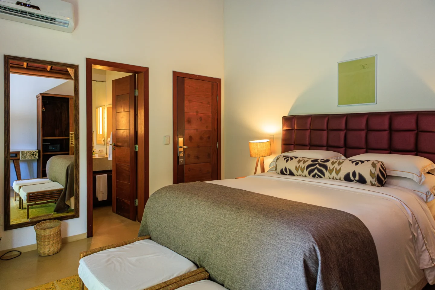 Quarto do Campo Bahia Hotel Villas Spa decorado com painel de madeira ripada e obras de arte