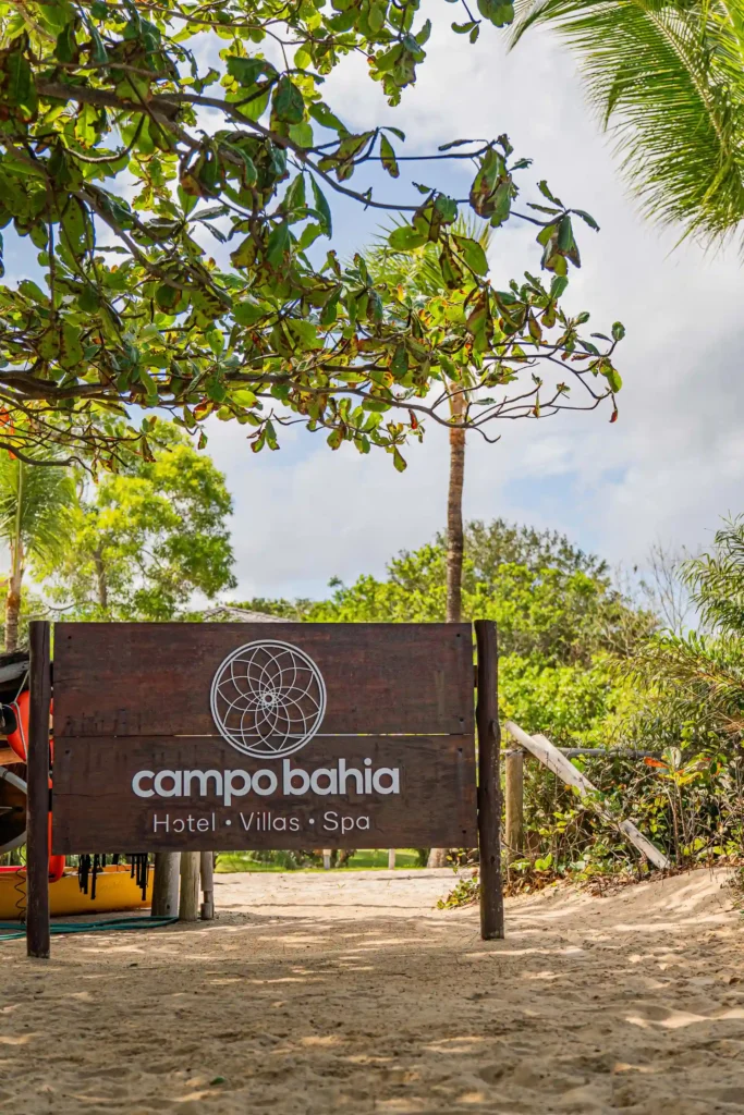 Placa de entrada do Campo Bahia Hotel Villas Spa em meio à vegetação nativa, a caminho da praia