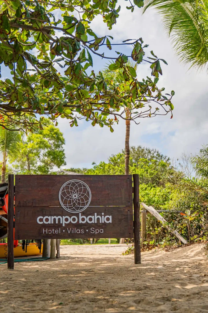 Placa de entrada do Campo Bahia Hotel Villas Spa em meio à vegetação nativa, a caminho da praia