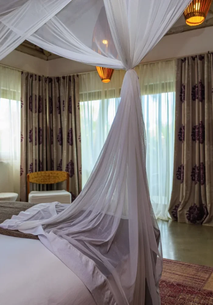 Quarto do Campo Bahia Hotel Villas Spa com dossel de tecido branco sobre a cama e televisão de parede