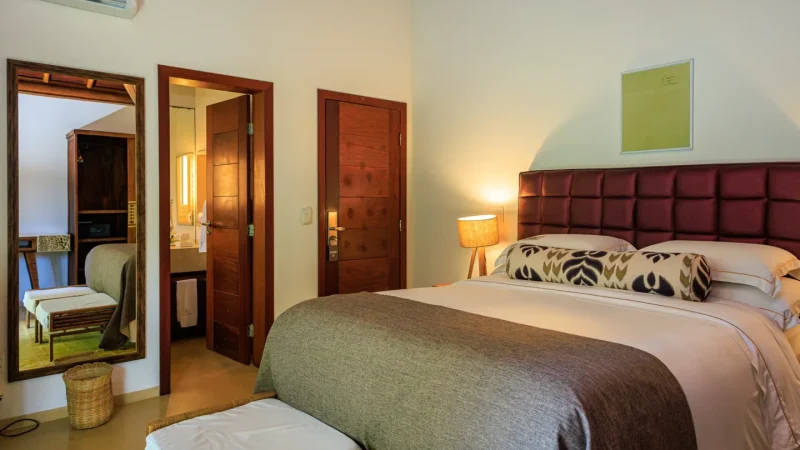 Quarto do Campo Bahia Hotel Villas Spa decorado com painel de madeira ripada e obras de arte