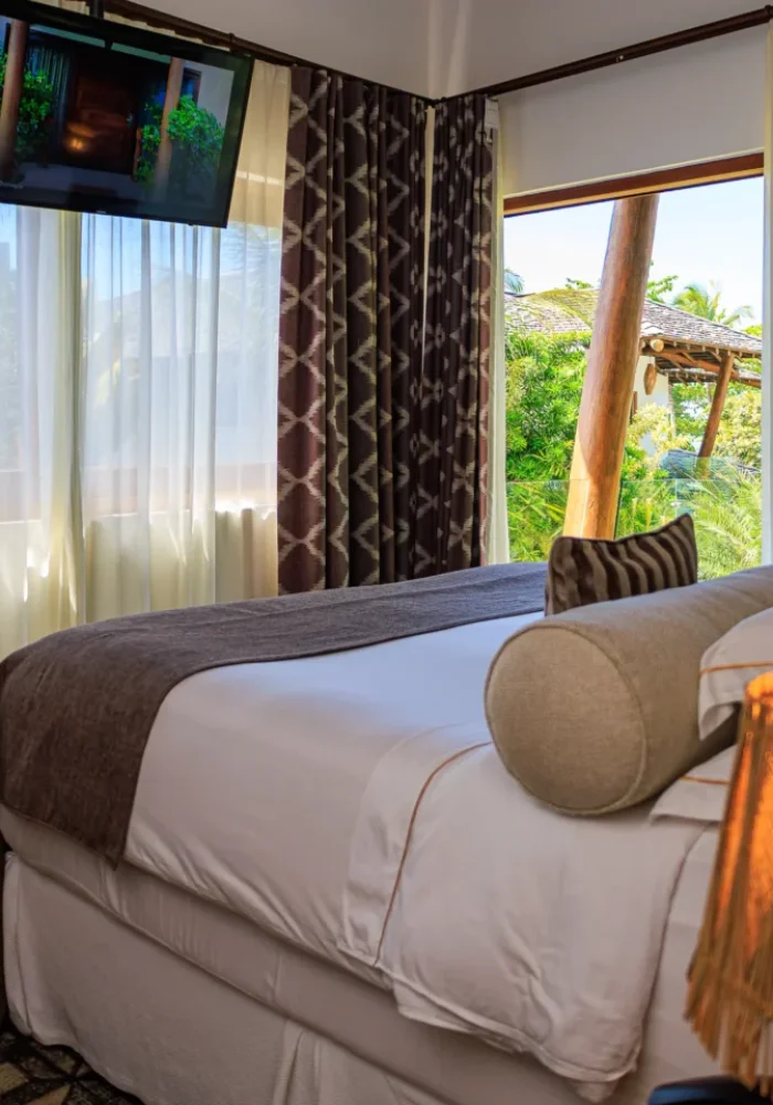 Quarto do Campo Bahia Hotel Villas Spa com cortinas listradas verticais e cama com almofadas decorativas