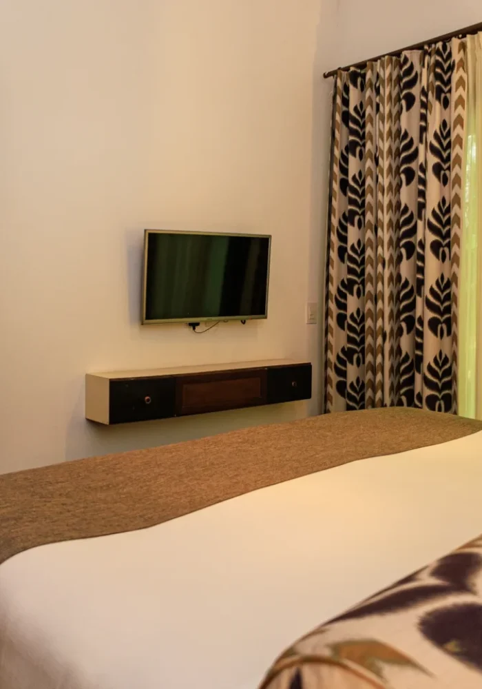 Quarto do Campo Bahia Hotel Villas Spa com cama de casal, televisão e cortinas estampadas