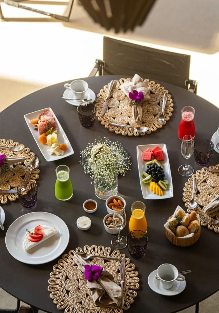 Mesa de café da manhã do Campo Bahia Hotel Villas Spa com frutas frescas, sucos naturais e pães servidos em cesta de fibra natural